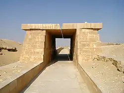 A paved way of white limestone covered with a roof made of massive stone blocks resting on equally massive walls.