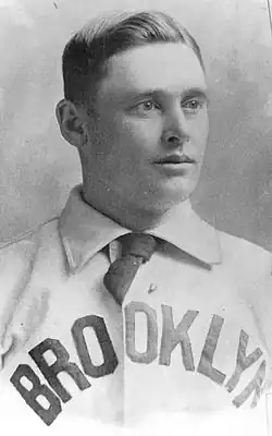 A man wearing a collared shirt with the words "BROOKLYN" at the front and a necktie.