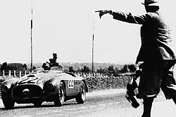 The winning Ferrari 166 MM crosses the finish line, with Chinetti driving