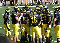 football team in yellow and blue uniforms in the huddle.