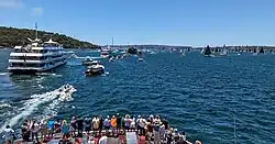 People looking towards the see where there are many boats and a big ship.