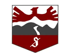 Vehicle insignia in the shape of a badge, depicting a red bird flying over grey hills.