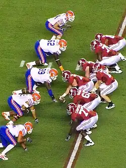 American football players on the line of scrimmage awaiting the snap.