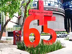 The sculpture features a number six, a number five, and a plus sign.