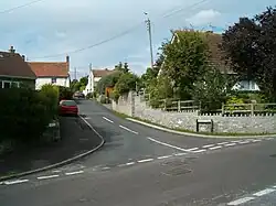 Street scene showing road junction with houses and cars