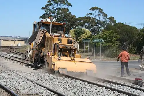 Levelling the ballast height between the rail