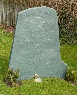 Irregular green gravestone standing in a grassy churchyard