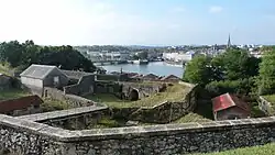 Photograph showing the internal walls of a stone fort overlooking a river with a town on the far side