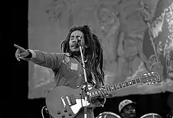 Black and white image of Bob Marley on stage with a guitar