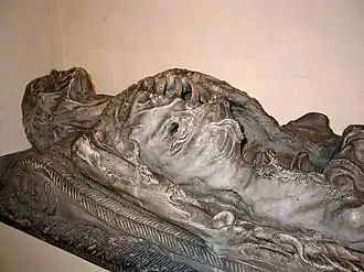 A sculpture of a dead body lying down, in an advanced stage of decay