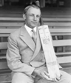 Man in double breasted suit, posing with a cricket bat.