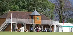 Cricket pavilion with players watching on a summers day
