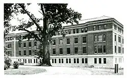 black and white photograph of a brick and stone laboratory building. a large tree stands in front of the building, with a bicycle leaned up against the tree