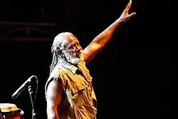 A man with dreadlocks holding his hand in the air