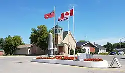 Flags and the war cenotaph in Cartwright with the Cartwright United Church in the background.