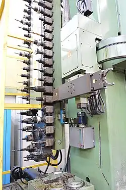 A chain type automatic tool changer with swiveling arm and two grippers, installed on a mill