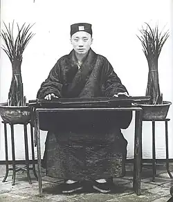 Upper Class Man Sitting at a Table Playing the Qin, 1906-1912.
