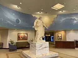 The St. George Visitors center south side entrance, with a copy of Bertel Thorvaldsen's Christus in the middle, showing a statue of a resurrected Jesus Christ, displaying the wounds in his body with open arms. A mural of the heavens is in the background.