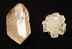 Crystallized sugar. Crystals on the right were grown from a sugar cube, while the left from a single seed crystal taken from the right. Red dye was added to the solution when growing the larger crystal, but, insoluble with the solid sugar, all but small traces were forced to precipitate out as it grew.