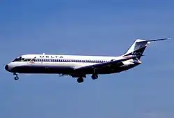 A midsized white twin-engine passenger jet in the air with landing gear deployed