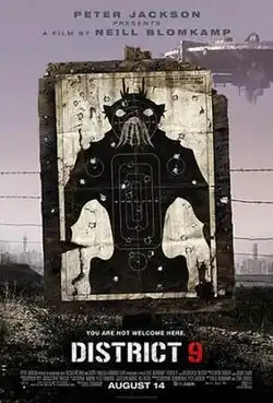 On dirty dusty ground, a black and white target practice poster of a bipedal insect-like alien creature stands, riddled with bullet holes. Barbed wire runs behind the poster and a large circular spaceship hovers in the background.