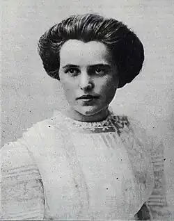 A black and white photo of a young woman posing for a portrait wearing all white with her hair up