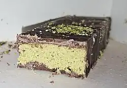 Photograph of a cut-through of a Dubai chocolate bar. The exterior is thin brown layer. The interior is a thick green textured paste.