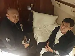 A dimly lit photo of Medialdea (left) and Duterte aboard a plane, shot from the inside