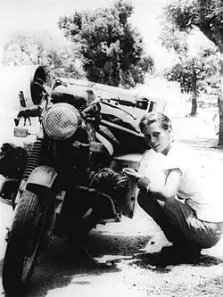 Black and white photo of Elspeth Beard crouched down next to a motorbike