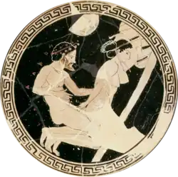 Interior of a Greek cup. The cup is black, with a white image of a woman on her knees and a man kneeing behind her; she is reaching behind her, grasping his penis.