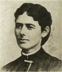 B&W portrait photo of a woman with dark hair in an up-do, wearing a dark blouse with white trim at the collar.