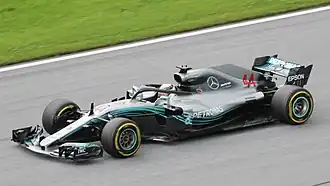 a grey open wheeled racing car is driven around a track