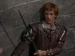 A color photograph of a young redheaded man in medieval dress