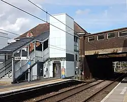 Railway tracks and platform, with lift and stairs to a bridge across the tracks