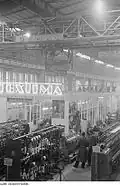 A Demag crane suspended above a factory floor handling textile machines in a company called Textima. Photographs by Roger and Renate Rössing from 1951