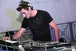 Photo of Gabry Ponte behind his DJ equipment and wearing headphones while performing onstage.