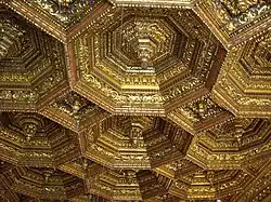 a renaissance wood ceiling gilded formed of octagons with a pendant in the center