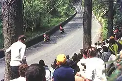TT race spectators at the exit to Glen Helen in 1969 with two travelling marshals passing by towards Creg Willey's Hill