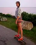 Skater riding her cruiser along the coast