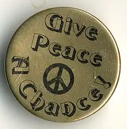 A "Give Peace a Chance" pin, likely a reference to the 1969 John Lennon song