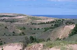 Sandy dunes with shrubs and Lake Superior in background