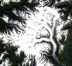 Satellite imagery of a roughly oval-shaped area of ice and snow surrounded by valleys in mountainous terrain