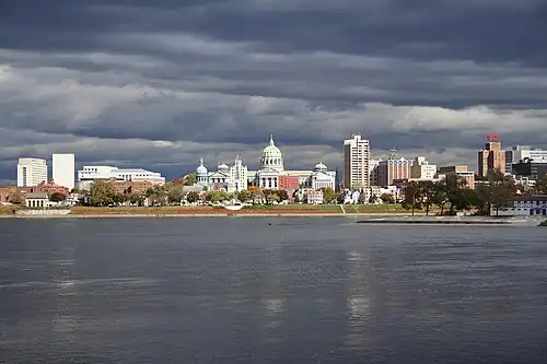 A city located on the opposite side of a large river, with a domed building in the city center.