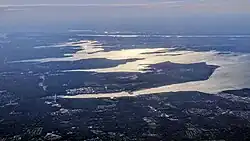 Greenery of the North Shore of Nassau County, looking west. The Cow Neck Peninsula is visible as the first peninsula at the center, with Manhasset Bay immediately above it and Hempstead Harbor immediately below it.