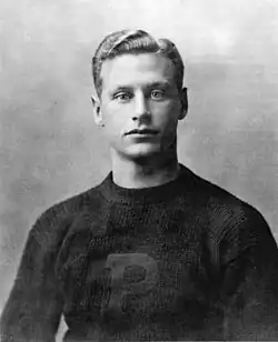 Black-and-white photo of the upper half of a young man wearing a sweater with a large "P" on the front
