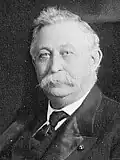 Portrait of a middle-aged to elderly white man with a large mustache in a suit.