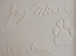 Jay Miner's signature from the top cover of a Commodore Amiga 1000 computer, along with his dog Mitchy's pawprint.