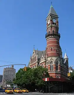Jefferson Market Library, once a courthouse and now a branch of the New York Public Library, seen during the day. The library is a brick structure with a round turret supporting a clock tower.