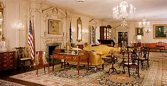 A drawing room holding the desk the Treaty of Paris was signed on and a painting depicting the event.