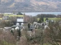 The village and a river with a bridge and dam on the left.
